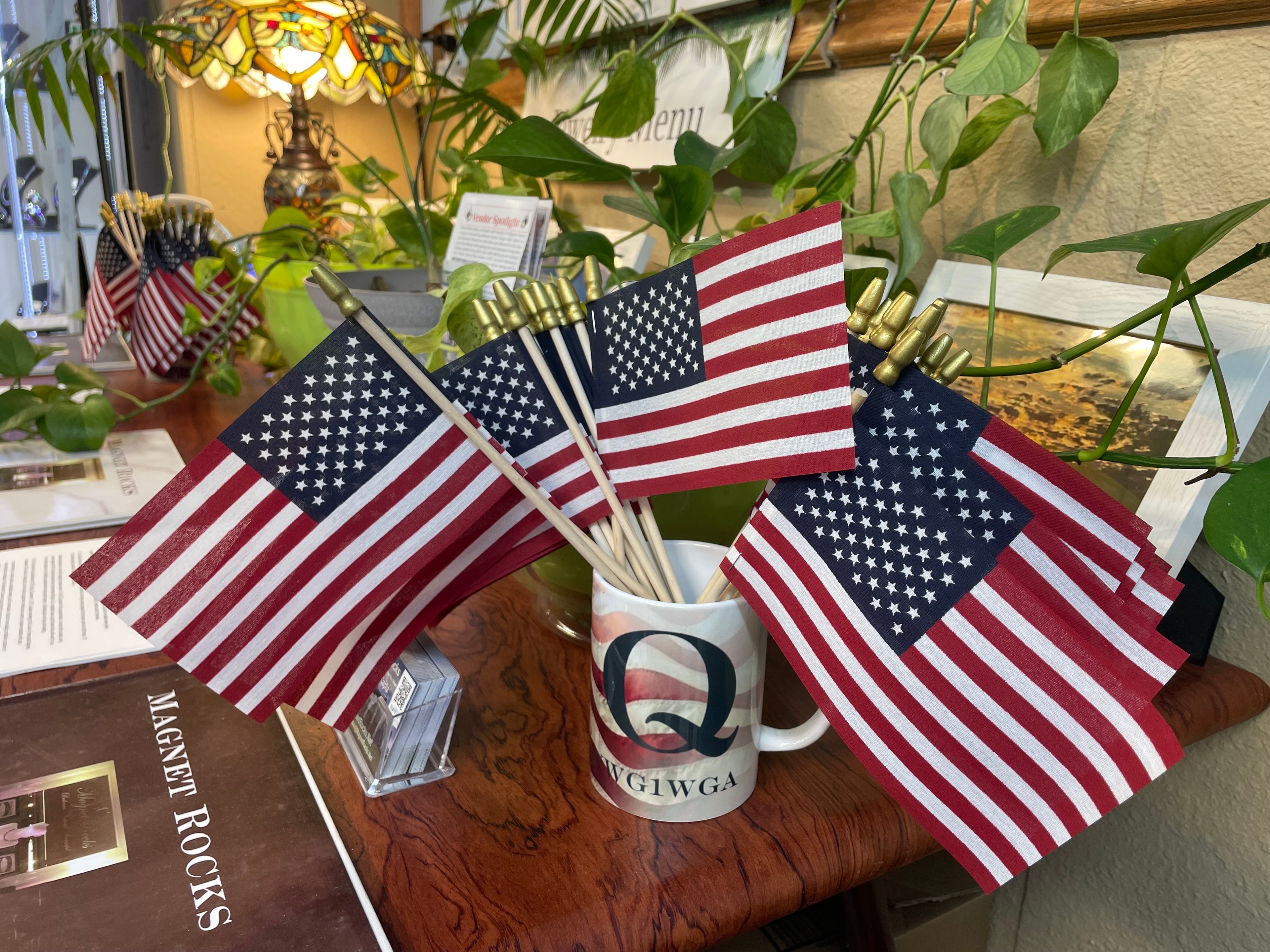 American flags in a mug on the Magnet Rocks counter, with the Magnet Rocks sign and booth materials visible